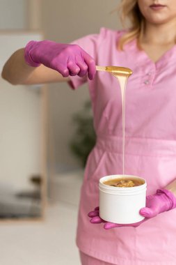 Yetenekli bir güzellik uzmanı huzurlu ve huzurlu bir ortamda tüylerini aldırmak için yumuşak bir balmumu sergiliyor.