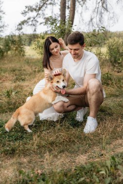 Çekici bir çift, neşeli Corgi 'leriyle dışarıda güneşli bir günün tadını çıkarır..