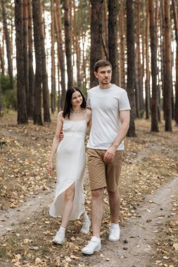 Huzurlu bir orman yolunda el ele yürürken derin sevgilerini ve bağlantılarını gösterirler.