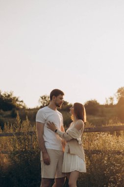 Sevgi dolu bir çift birbirine sarılır, neşe ve derin aşkta kaybolur, büyüleyici bir günbatımıyla çevrelenir, bu güzel ortamda bağlarını ve doğanın huzurunu yansıtır.