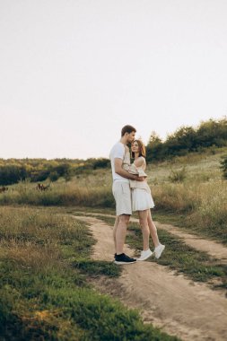 Neşeli ve hayat dolu bir çift, yeşillik ve açık alanlarla çevrili, doğada aşkı yakalamak için ideal, pitoresk bir manzarada hassas ve samimi bir anı paylaşıyor.