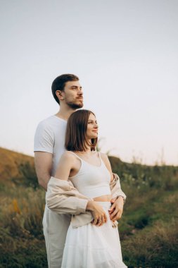 Çarpıcı ve sakin bir açık hava ortamında, güzel bir çift birbirine yakın durur, romantizmini, sıcaklığını ve derin bağlantılarını sergilerler nefes kesici bir günbatımı arka planına karşı.