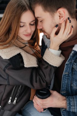 Sıcak, romantik bir kucaklaşma, şık kış kıyafetleri giymiş ve anın tadını çıkaran bir çift arasında.