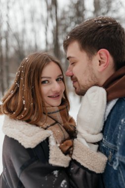 Neşeli bir çift, karlı bir arazide, kalplerinde sevgi ve sıcaklık gösteren hassas bir anı paylaşır.