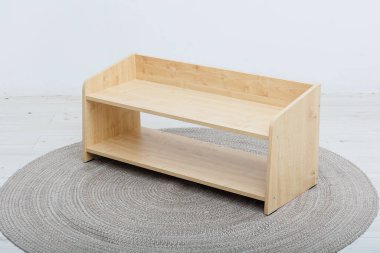 Çok güzel hazırlanmış ahşap bir raf yumuşak, yuvarlak bir halının üzerine yerleştirilmiş, odanın estetiğini güçlendiriyor.