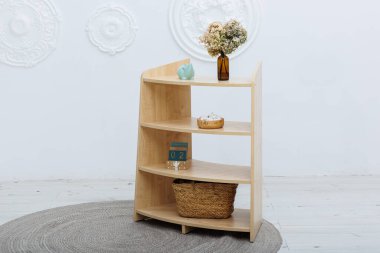 Güzel işlenmiş ahşap bir rafta, sevimli bir domuz kumbarası var. Yanında da enfes bir hasır sepet var.