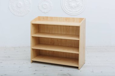 Üç farklı seviyeye sahip güzel bir ahşap raf, el değmemiş beyaz bir duvara karşı yerleştirilmiş, uzaya zarafet ve işlevsellik katıyor.