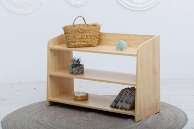 Güzel işlenmiş bir hasır sepet zarif bir şekilde sağlam ahşap bir rafın üzerinde duruyor, etrafındaki dekorun cazibesini arttırıyor.