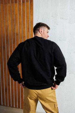 Siyah eşofman üstü giymiş bir adamın, parlak sarı bir pantolon giyip çarpıcı bir karşıtlık yaratan bir adamın arka görüntüsü.,