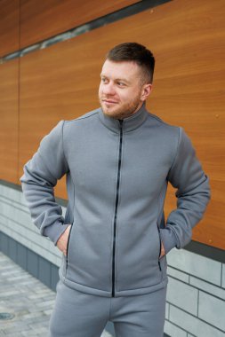 Düzgün kesilmiş sakalı olan bir adam şu anda görünüşünü ve tarzını mükemmel bir şekilde tamamlayan şık gri bir ceket giyiyor.