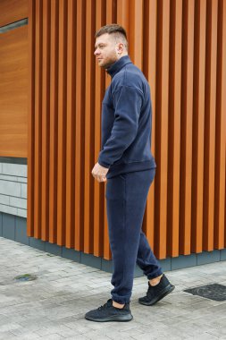 Sakallı bir adam, çevresine dikkat çeken büyüleyici bir ahşap binanın önünde yürüyor.