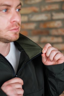 Bir adam fermuarı olan siyah bir ceket giyiyor. Bu ceket çeşitli hava koşullarında oldukça işlevsel ve şık olabilir.