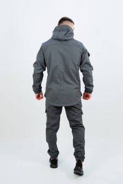 Arkadan bir adam görülüyor, şık gri bir ceket giymiş, kapüşonlu, açık hava kış macerası için mükemmel.