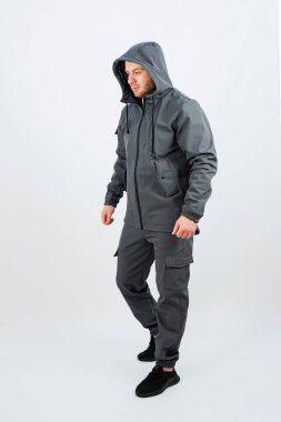 Bir adam şık, gri bir ceket giyerken görüldü. Rahat bir başlık giyiyordu. Kıyafetine hem sıcaklık hem de moda katıyordu.