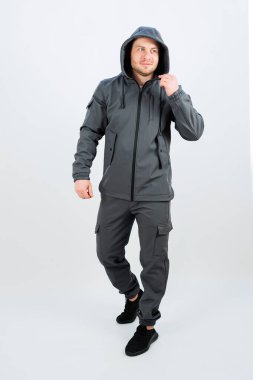 Bir adam şık, gri bir ceket giyiyor. Kapüşonu rahat, açık hava aktiviteleri ve kış koşulları için uygun hale getiriyor.