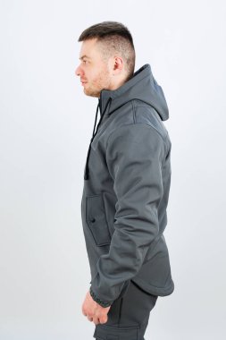 Bir adam şık, gri bir ceket giyiyor. Üzerinde rahat bir başlık var. Hem sıcak hem de sıradan bir görünüm katıyor.