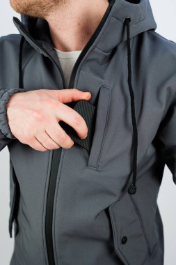 Modaya uygun gri bir ceket giyen bir adamın, bir eli ceketinin cebinde rahatça saklanır.