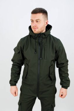 Parlak yeşil bir ceket giyen ve elementlerden korunmak için uygun bir başlık takan bir adam.