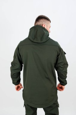 Kapüşonlu yeşil bir ceket giyen, askeri kamuflaj tarzını ve uygulanabilirliğini temsil eden bir adamın arka görünüşü.