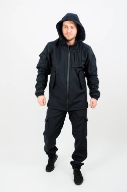 Kapüşonlu siyah bir ceket giyen bir adam, soğuk hava aktiviteleri için kıyafetine biraz stil ve sıcaklık katıyor.