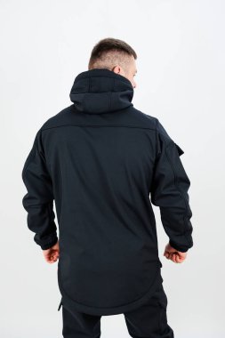 Kapüşonlu şık bir siyah ceket giyen bir adamın arka görünüşü onu kış gezileri ve açık hava aktiviteleri için mükemmel kılıyor.