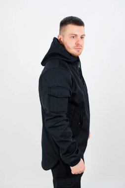 Bir adam, serin hava koşullarında sıcak ve konforlu bir başlık içeren şık siyah bir ceket giyiyor.