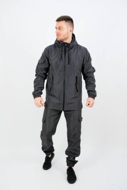 Şu anda bir adam şık siyah bir ceket giyiyor ve şık kıyafetini tamamlayan parlak siyah bir pantolon giyiyor.