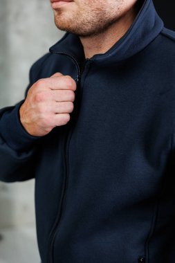 Şık bir sakalı olan bir adam mavi bir ceket giyer ve bu portrede modern moda anlayışını sergiler.