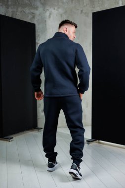 Tarz sahibi siyah bir ceket giyen bir adamın arkası, aynı pantolonu giyen, zahmetsizce havalı bir görünüm sergileyen bir adam.