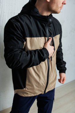Bir adam şık, siyah ve bronz bir ceket giyer. Kıyafetine çok yakışır. Benzersiz moda anlayışını gözler önüne serer.
