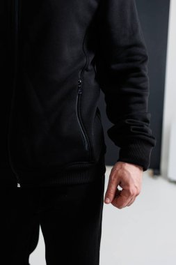 Tarz sahibi siyah bir ceket giyen bir adam görünür. Kenarında pratik bir fermuar bulunur. Benzersiz tasarım unsurlarını sergiler.