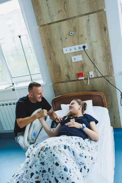 Bakıcı koca, hamile kadının elini tutuyor. Çocuk doğururken genç bir kadına yardımcı olan koca. Doğum sırasında destek ve tıbbi bakım kavramı.