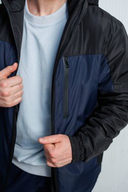Bir adam şu anda şık bir fermuar tasarımı içeren mavi ve siyah bir ceket giyiyor ve bu da onu daha serin hava için son moda bir seçim yapıyor.