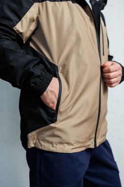 Havalı bronz tenli ve siyah rüzgarlık ceketli bir adam ellerini rahatça cebine sokabilir.