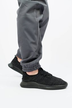 İçinde siyah ayakkabılar ve gri pantolonlar bulunan şık bir kıyafet giymiş bir insan, moda ve rahatlık duygusunu ön plana çıkarıyor.