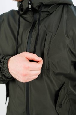 Canlı yeşil bir ceket giyen bir adam elini rahat bir şekilde şık dış giyiminin cebine sokuyor.