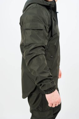 Şık yeşil bir ceket giymiş bir adam bileğine bir saat takıyor. Göze çarpıyor ve görünüşünü mükemmel tamamlıyor.