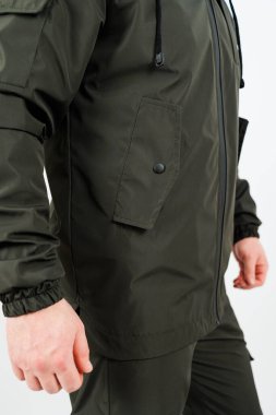 Bir adam canlı yeşil bir ceket ve şık siyah bir pantolon giyerken, yürürken cesur bir moda ifadesi sergilerken görülebilir.