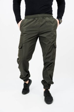 Bir adam, hem işlevsel hem de modaya uygun yeşil kargo pantolonları ile tamamlanmış şık siyah bir gömlek giyerken görülüyor.