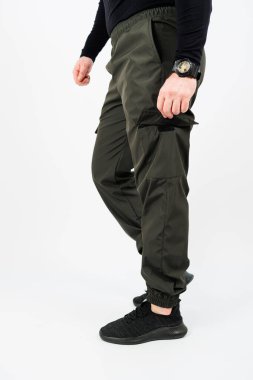 Bir adam yeşil kargo pantolonu ile birlikte siyah bir gömlek giyiyor. Rahatlığı ve işlevselliği için çok popülerdir.