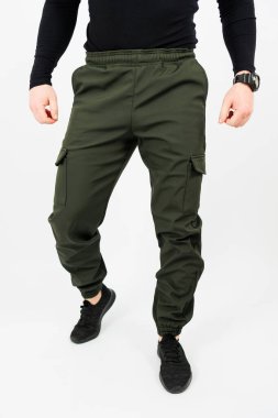 Bir adam, oldukça şık bir çift yeşil kargo pantolonu ile tamamlanmış şık siyah bir gömlek giyerken görülüyor.