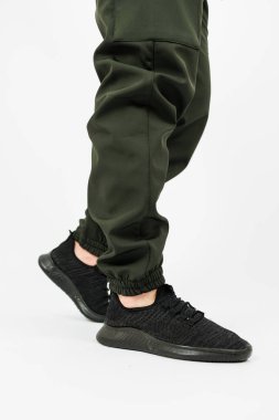 Tarz sahibi siyah ayakkabılar ve kalabalıkta göze çarpan yeşil pantolonlar giyen bir insan etrafta dolaşıyor.