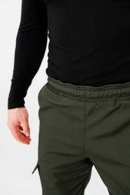 Siyah gömlekli ve şık yeşil pantolonlu bir adam sokakta güvenle yürürken görülüyor.