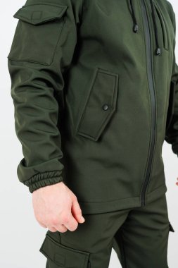 Bir adam siyah fermuarlı, şık yeşil bir ceket giyiyor. Hem şık hem de çeşitli durumlar için kullanışlı.