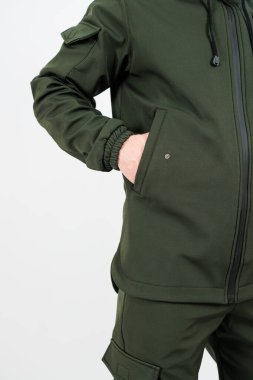 Şık ve göz alıcı yeşil bir ceket giyen bir adamın iki eli de ceketinin cebinde rahatça dinlenir.