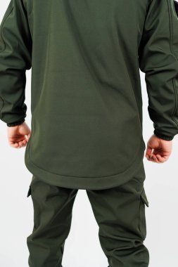 Canlı yeşil bir gömlek giymiş, kargo pantolonuyla eşleştirilmiş, günlük tarzlarını vurgulayan bir bireyin arka planı.