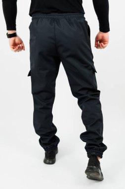 Süslü, siyah bir kargo pantolonu giyen, pratik ceplerini ve moda tasarımlarını sergileyen bir adamın arka planı.