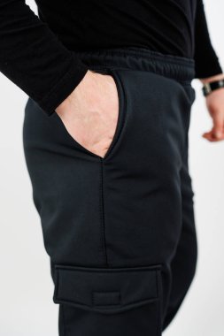 Siyah kargo pantolonu giymiş bir adam elini cebine sokmuş, rahat ve rahat görünüyor.
