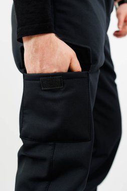 Süslü siyah pantolon giyen biri elini ceplerinden birine sokmuş, belki de bir şeyler düşünüyordur.