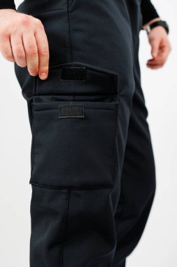 Bir insan, birden fazla cebi olan, hem işlevsel hem de çağdaş görünümlü şık siyah bir kargo pantolonu giyer.